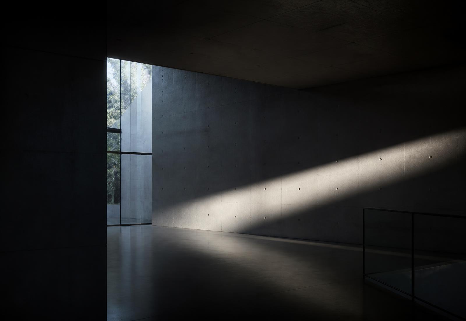 Daylight raking across a concrete wall in a minimal architectural interior